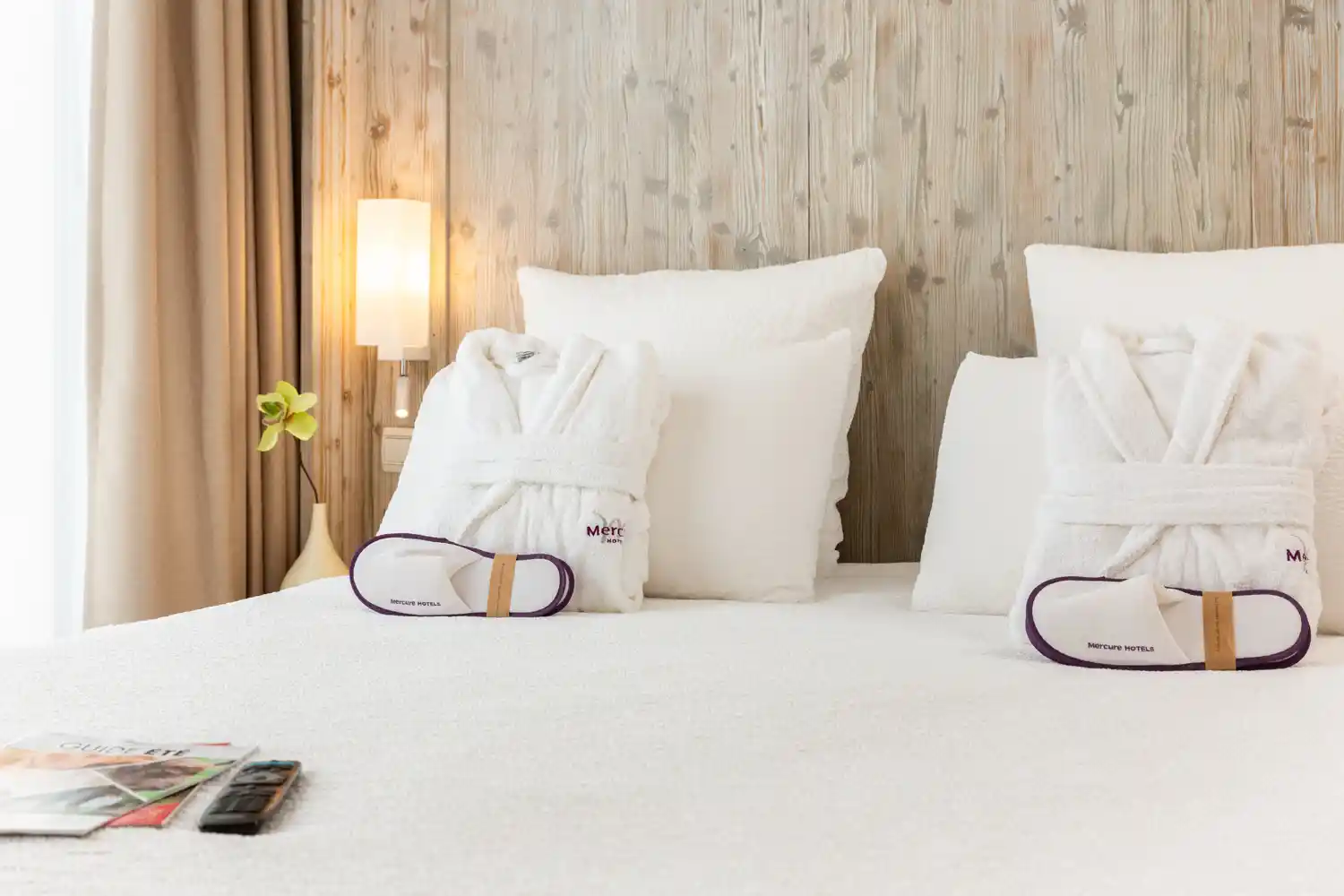 Détail d'une chambre d'hôtel avec des chaussons sur un lit